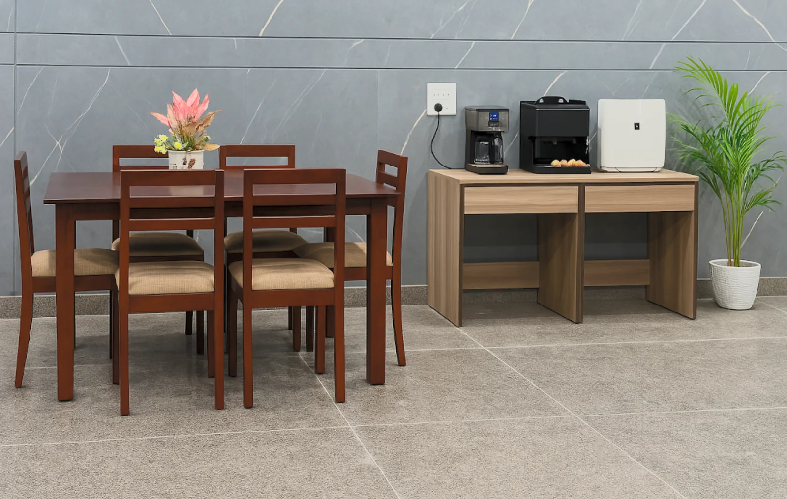 Four-seat dining table and a clean appliance counter against a grey wall.